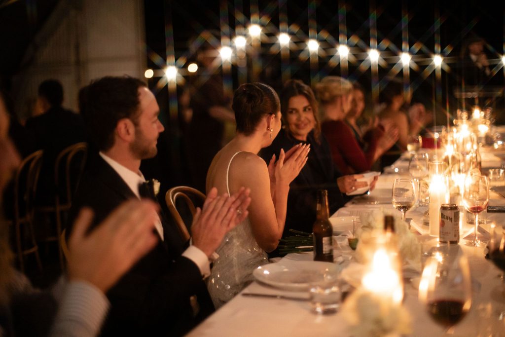 Romantic candlelit wedding reception dinner at Jimbour House in Queensland, with the bride and groom seated at a long banquet table under string lights during their destination celebration.