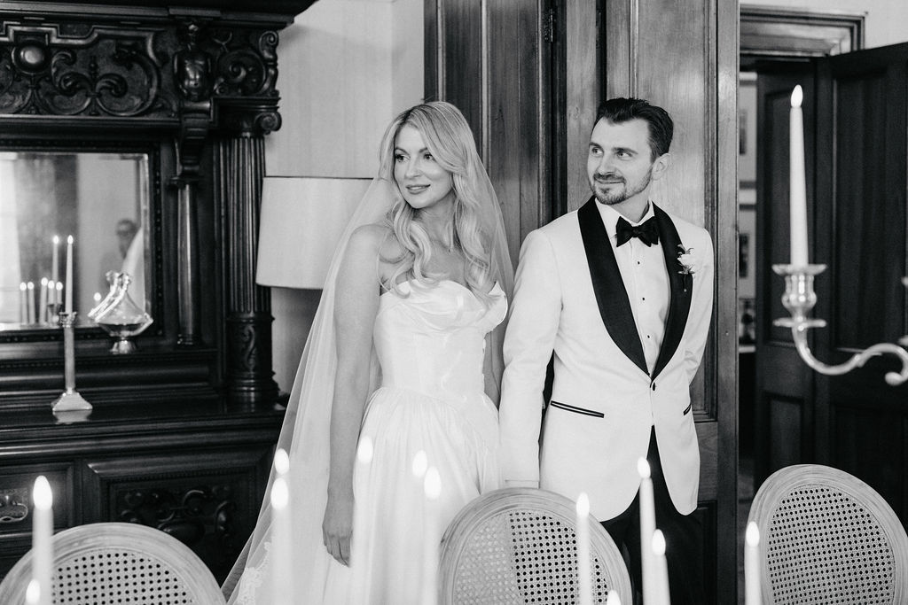 Bride and groom enter a candlelit dining room at Jimbour House for an intimate wedding reception, dressed in black tie attire with vintage-inspired styling.
