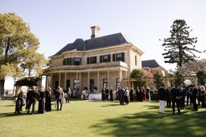 Guests gather on the Eastern Lawn at Jimbour House for a garden cocktail hour, with the sandstone homestead and verandah in the background at a Queensland wedding venue