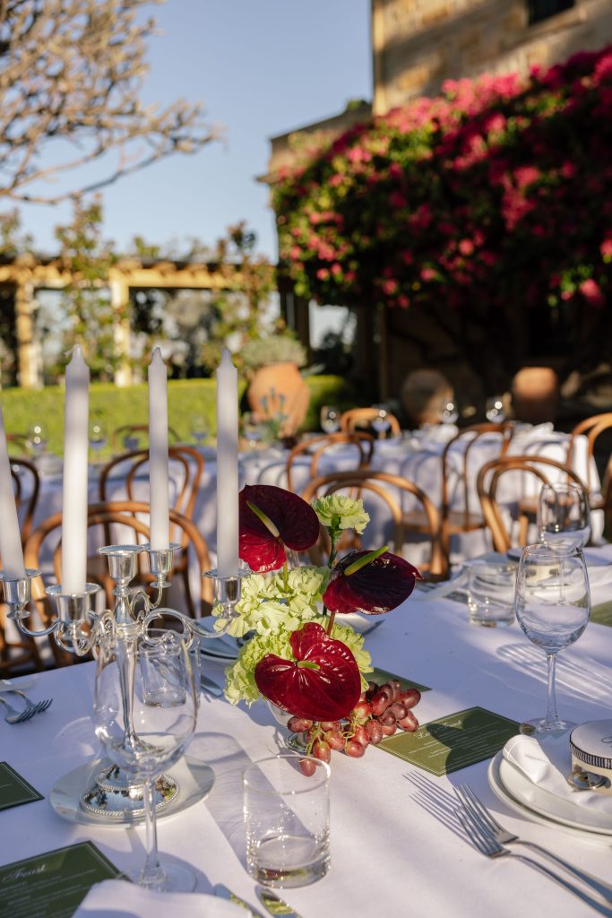 Wedding reception table styling with candelabra, anthurium florals and grapes set on long banquet tables outdoors at Jimbour House Queensland