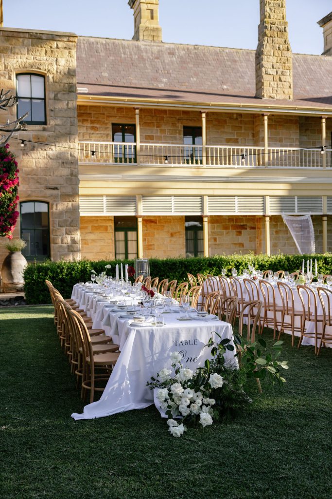Outdoor wedding reception setup with long banquet tables, white linens and floral styling on the lawn at Jimbour House Queensland
