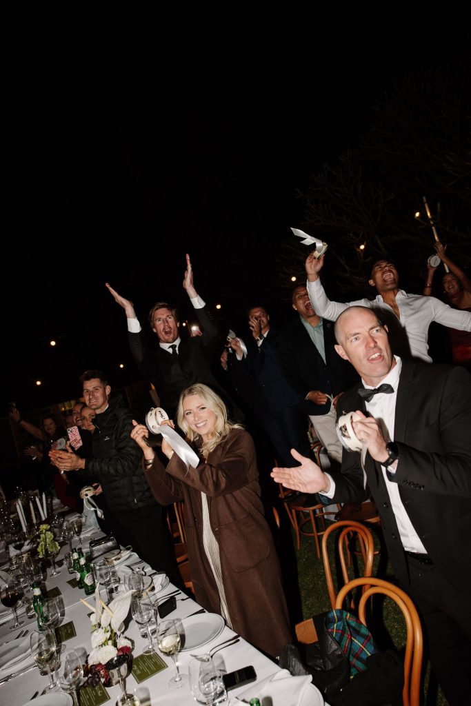 Wedding reception celebration with guests dancing and waving napkins at an outdoor evening reception at Jimbour House Queensland
