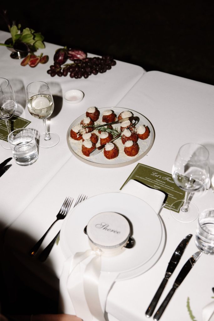 Wedding reception table with plated canapés, wine glasses and personalised place setting during evening dining at Jimbour House Queensland