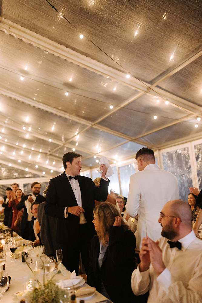 Wedding guests celebrating inside a clear marquee with string lights during a reception at Jimbour House.